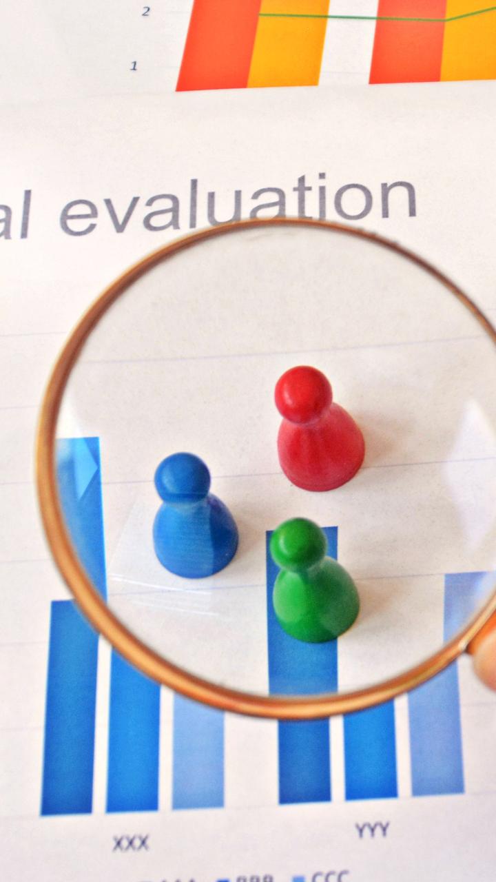 Colored game pieces under magnifying glass with chart background