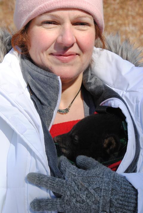 Jennifer with a black bear cub in her coat